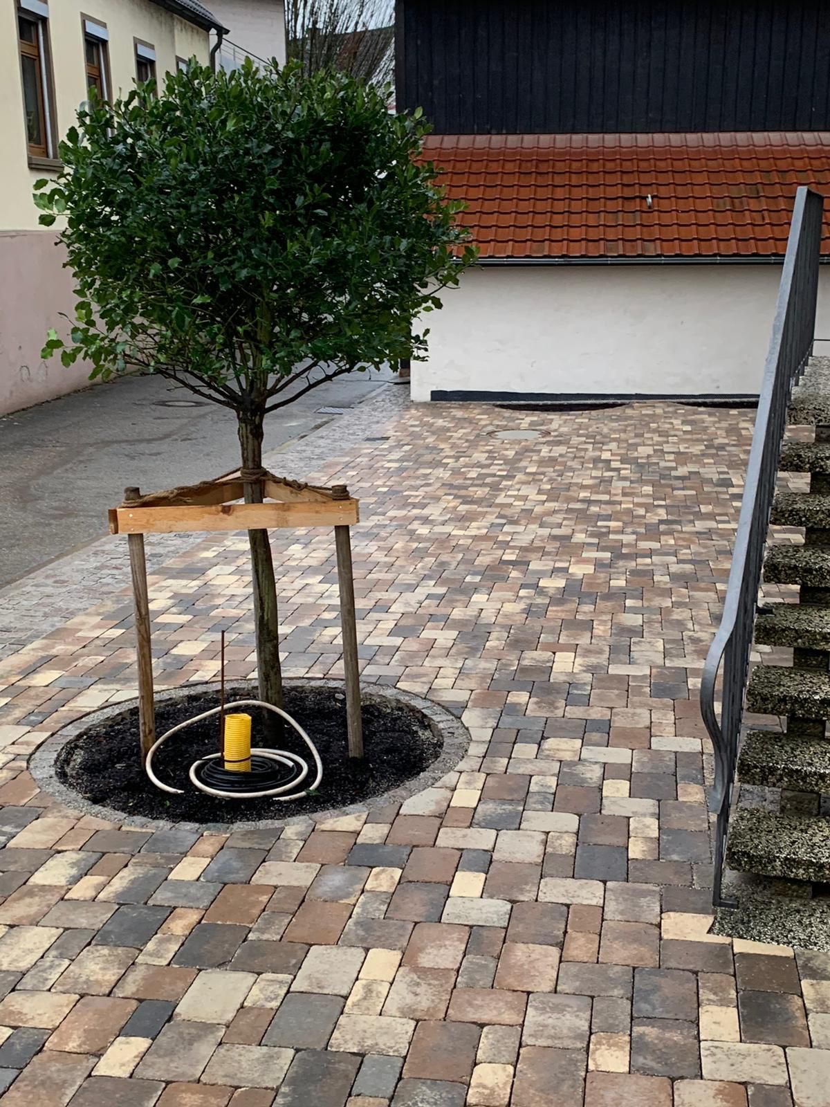 Verlegung von Pflaster und Schachtabdeckung mit Natursteinen integriert.